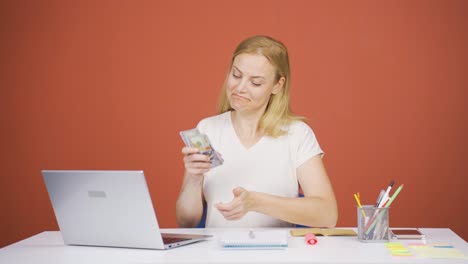Woman-looking-at-laptop-counting-money.